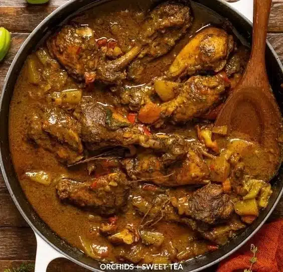 Plate of authentic Jamaican curry chicken with rice and vegetables