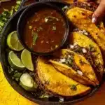 Delicious birria tacos with flavorful broth and tender meat served on a plate