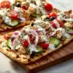 Delicious Greek Chicken Flatbread topped with fresh vegetables and tzatziki sauce
