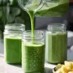 Delicious green smoothie in a glass with fresh ingredients on the table