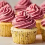 Lemon poppy seed cupcakes with vibrant blackberry frosting on a decorative plate