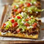 Homemade Crescent Roll Taco Pizza topped with cheese, salsa, and fresh toppings.