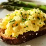 A bowl of fluffy cottage cheese scrambled eggs topped with herbs.